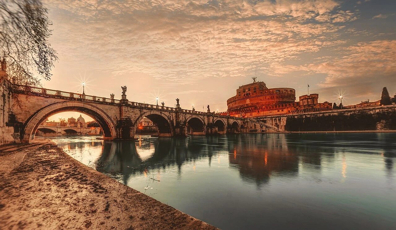 Location view of Ponte Sant’Angelo and Castel Sant’Angelo across the Tiber at sunset