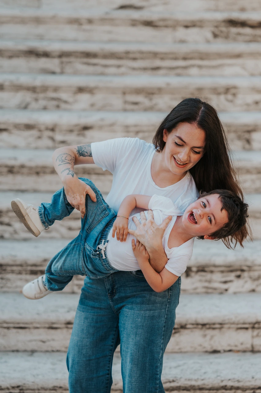 Mother laughing with her young son on stone steps during a family photoshoot in Arezzo.