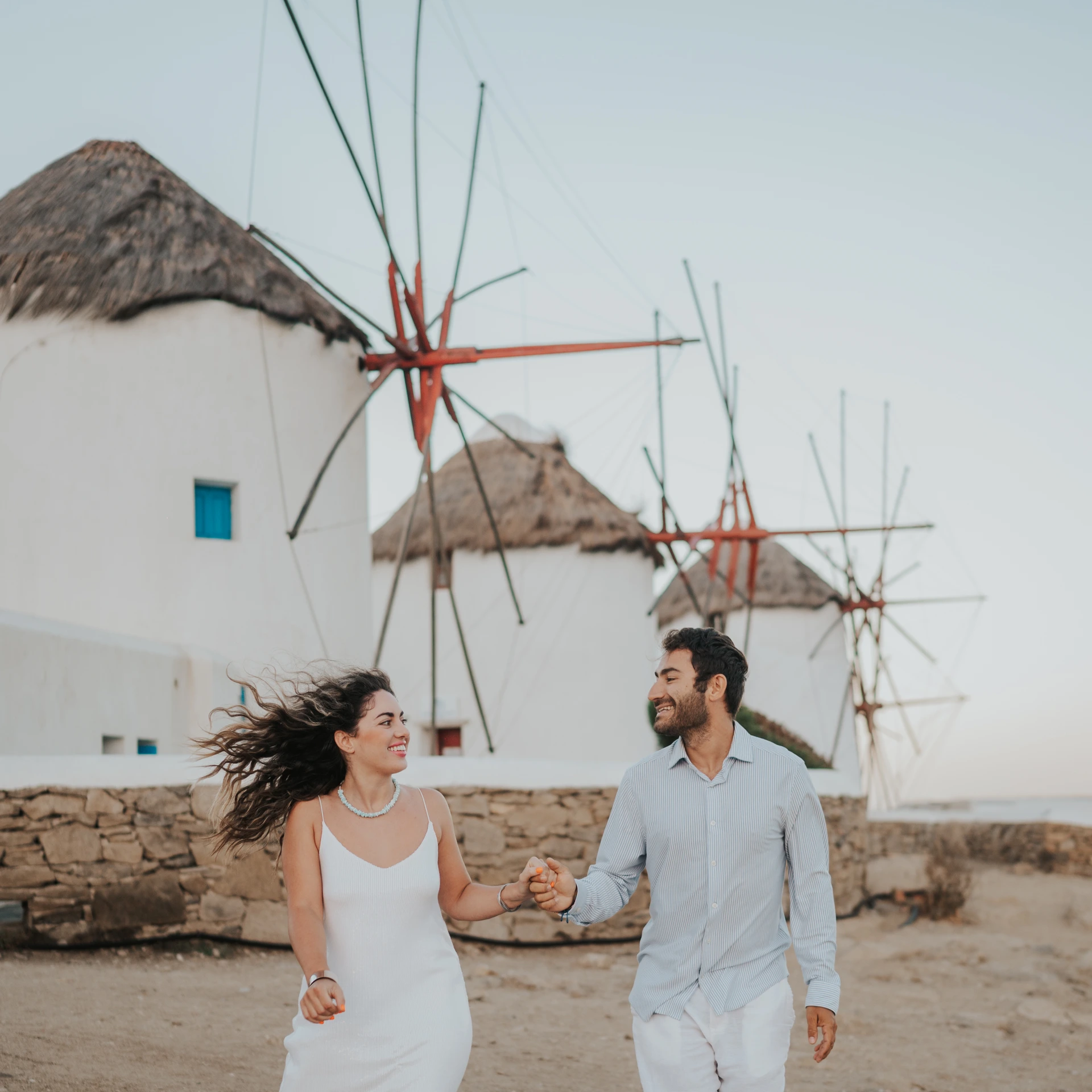 Couple walking in front of the windmills of Mykonos