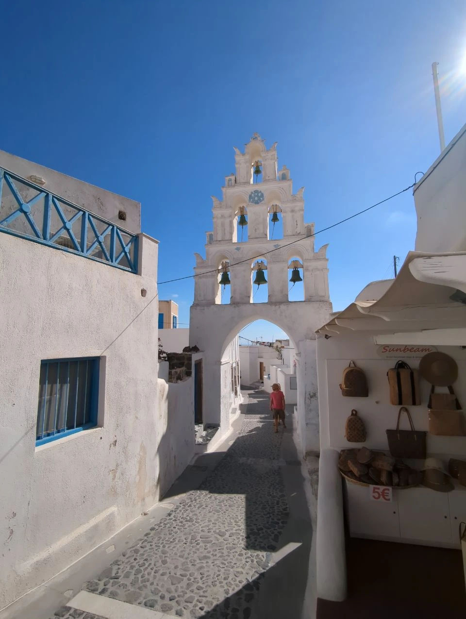 White bell-tower arch spanning a village street in Megalochori