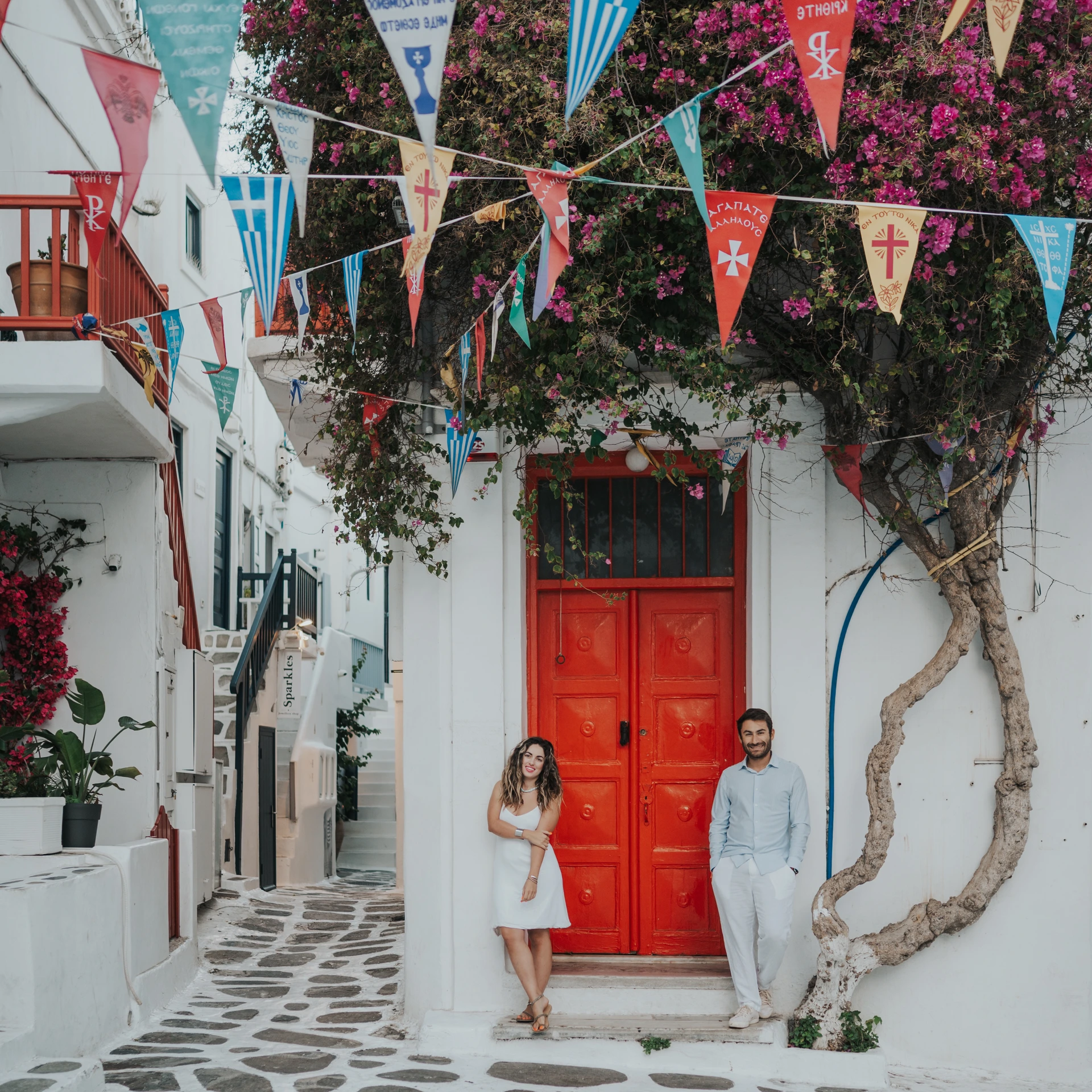Couple beside a red door and bougainvillea in Mykonos Town