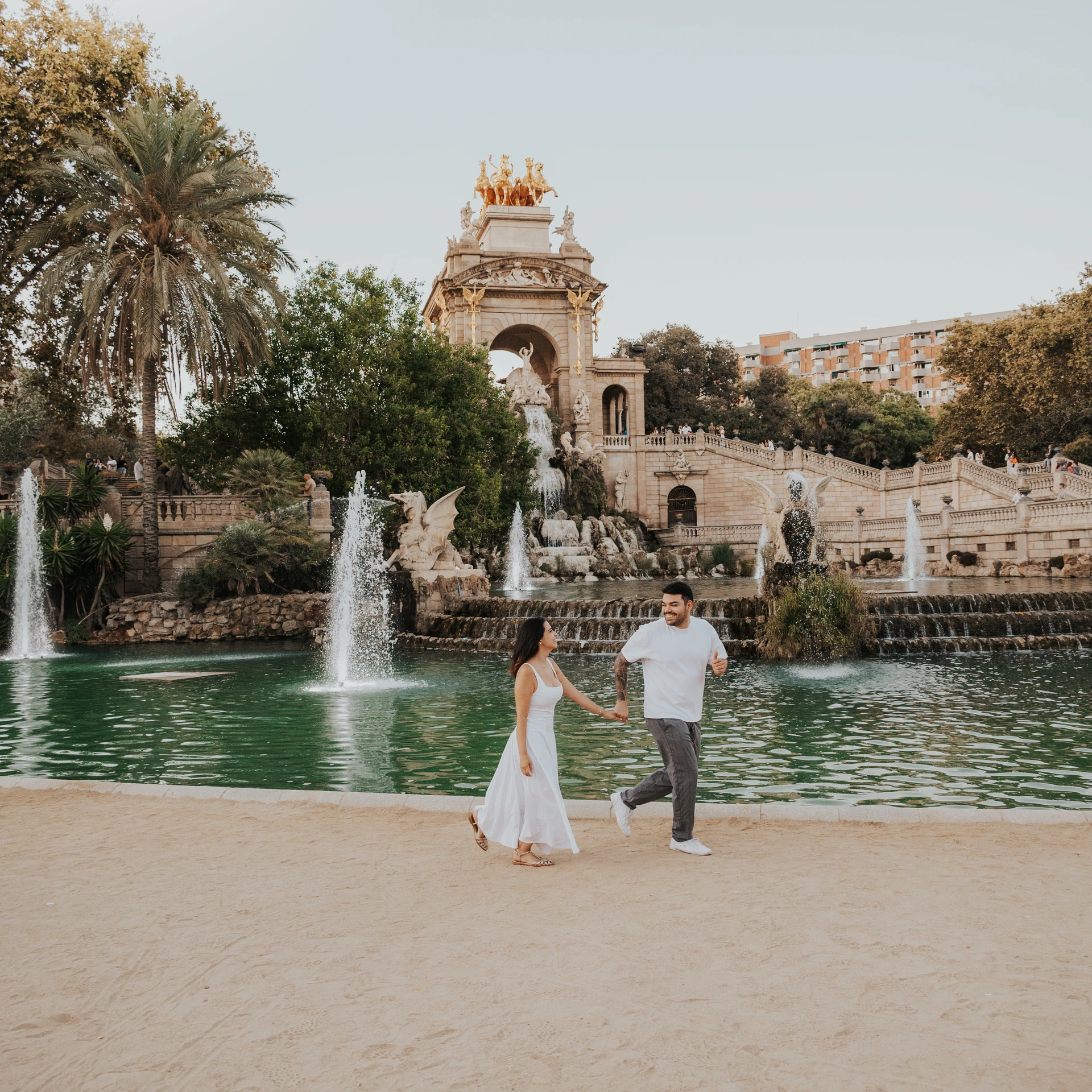 Una pareja camina de la mano junto a las fuentes de la Cascada Monumental en el Parc de la Ciutadella durante una sesión de fotos de pareja en Barcelona.