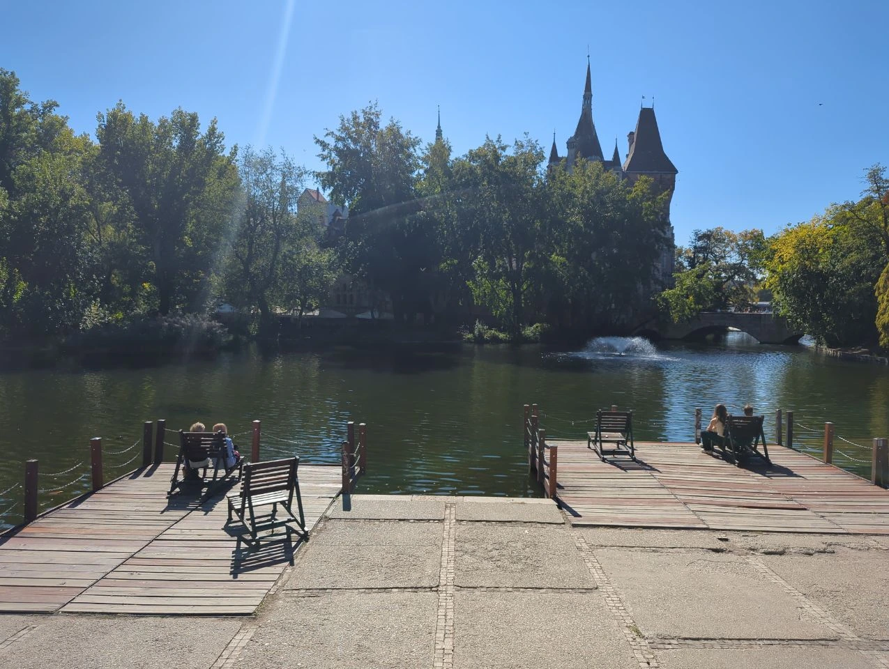 Public seats on decks beside the lake in City Park with the castle beyond