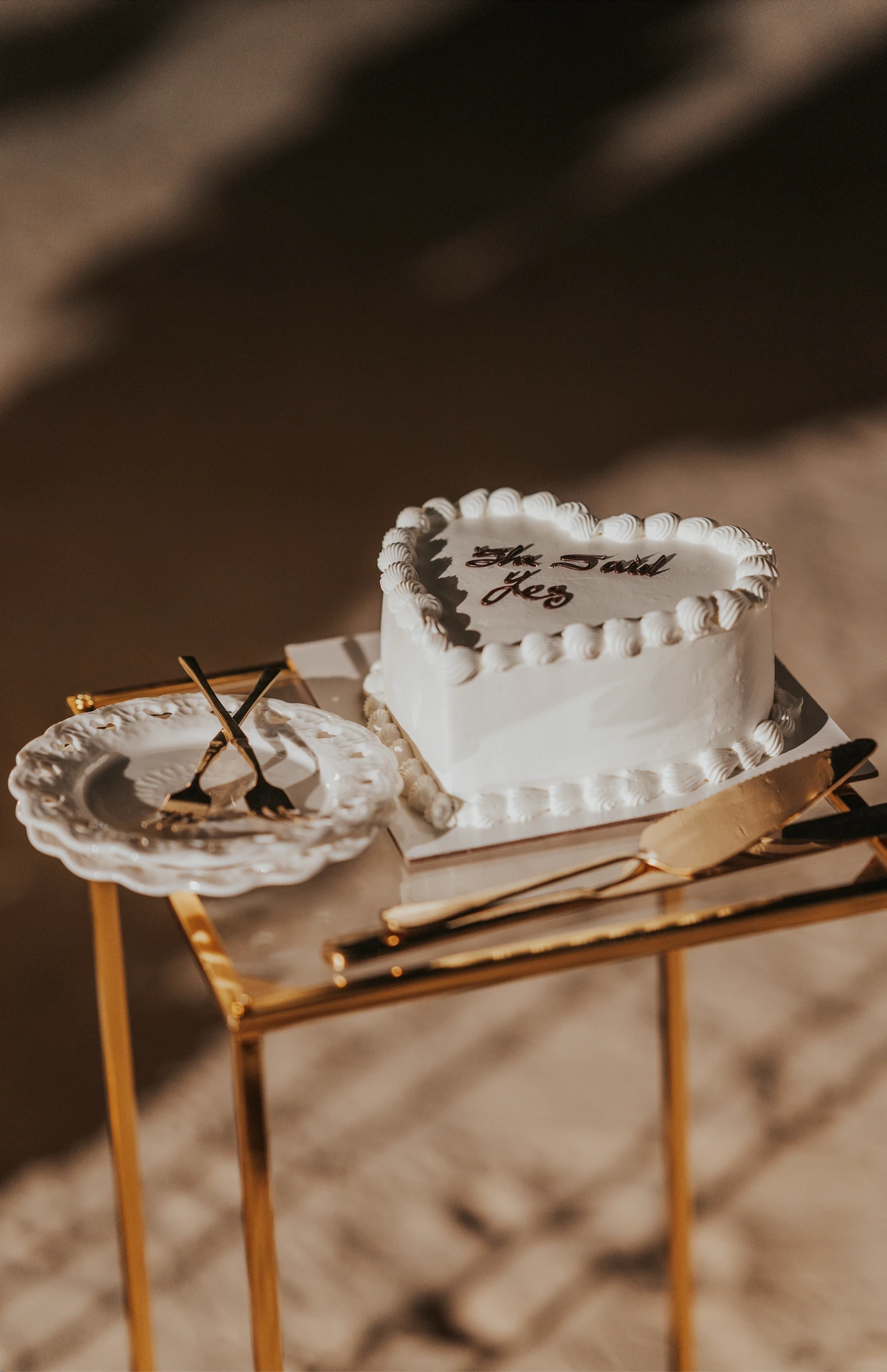 A heart-shaped cake and serving set are styled on a small table at Dubai beach as an add-on detail for a proposal setup.