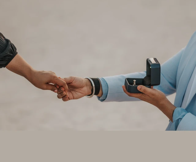 Close-up of an open ring box during a proposal setup in Dubai, with the couple holding hands in the background.