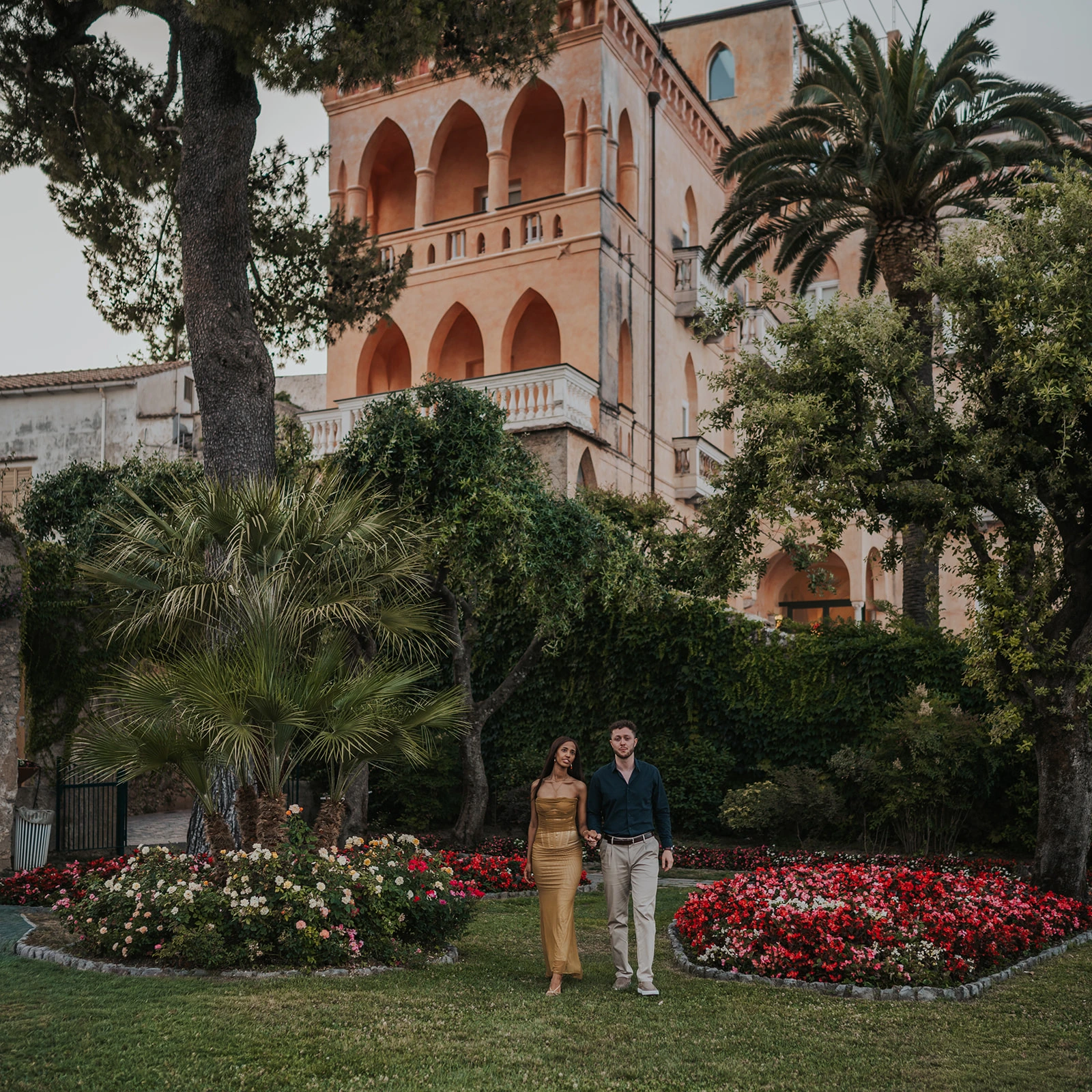 Couple standing in a garden before a pink villa on the Amalfi Coast