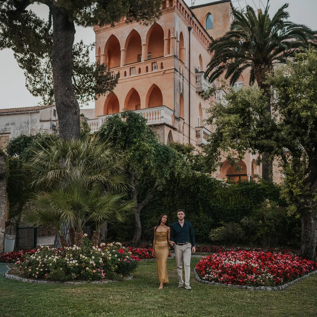 Couple standing in a garden before a pink villa on the Amalfi Coast
