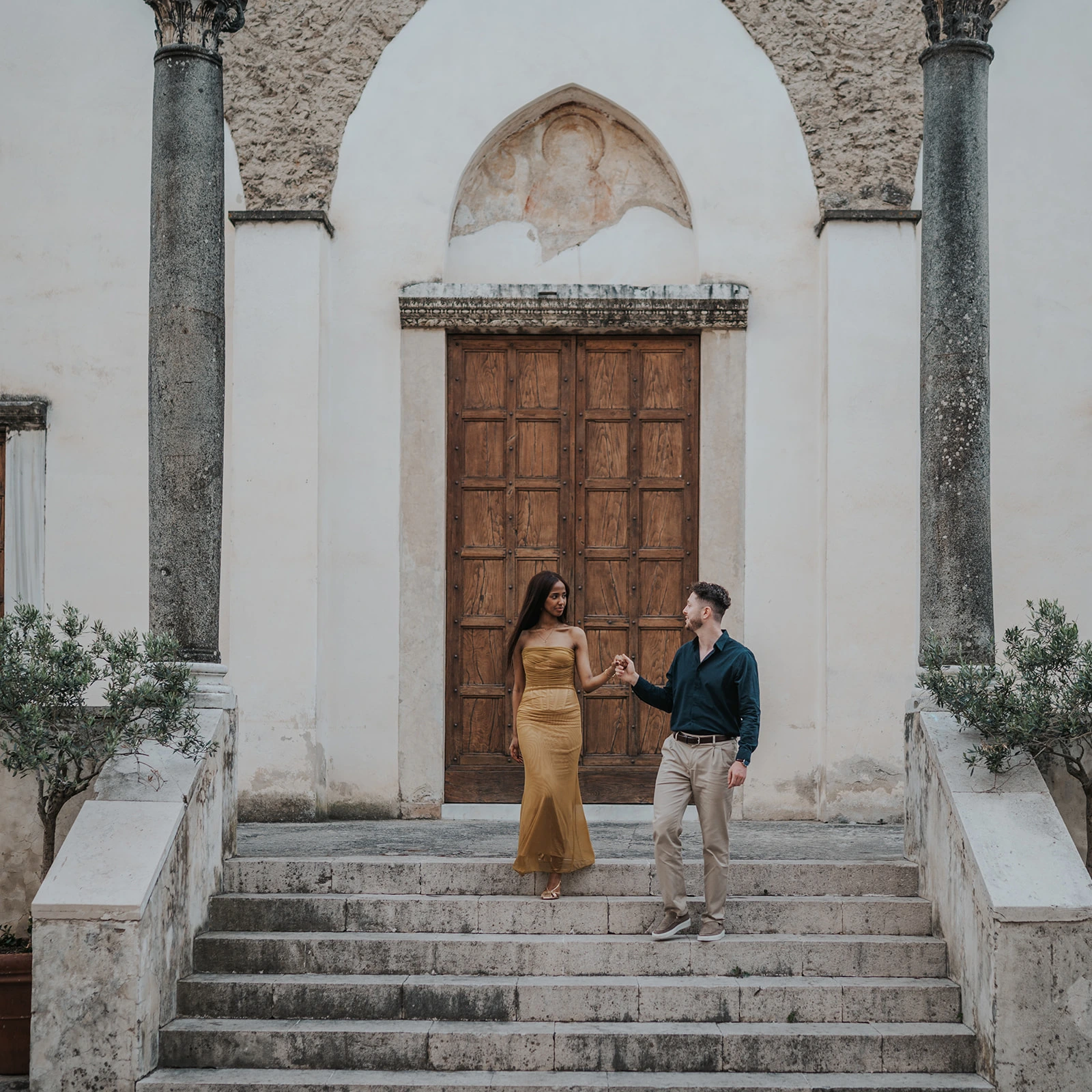 Couple on stone steps in front of a church doorway on the Amalfi Coast