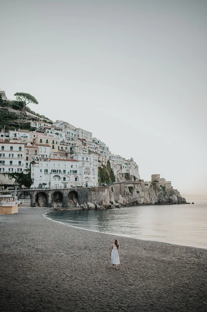 Person walking on Amalfi beach beneath the waterfront buildings