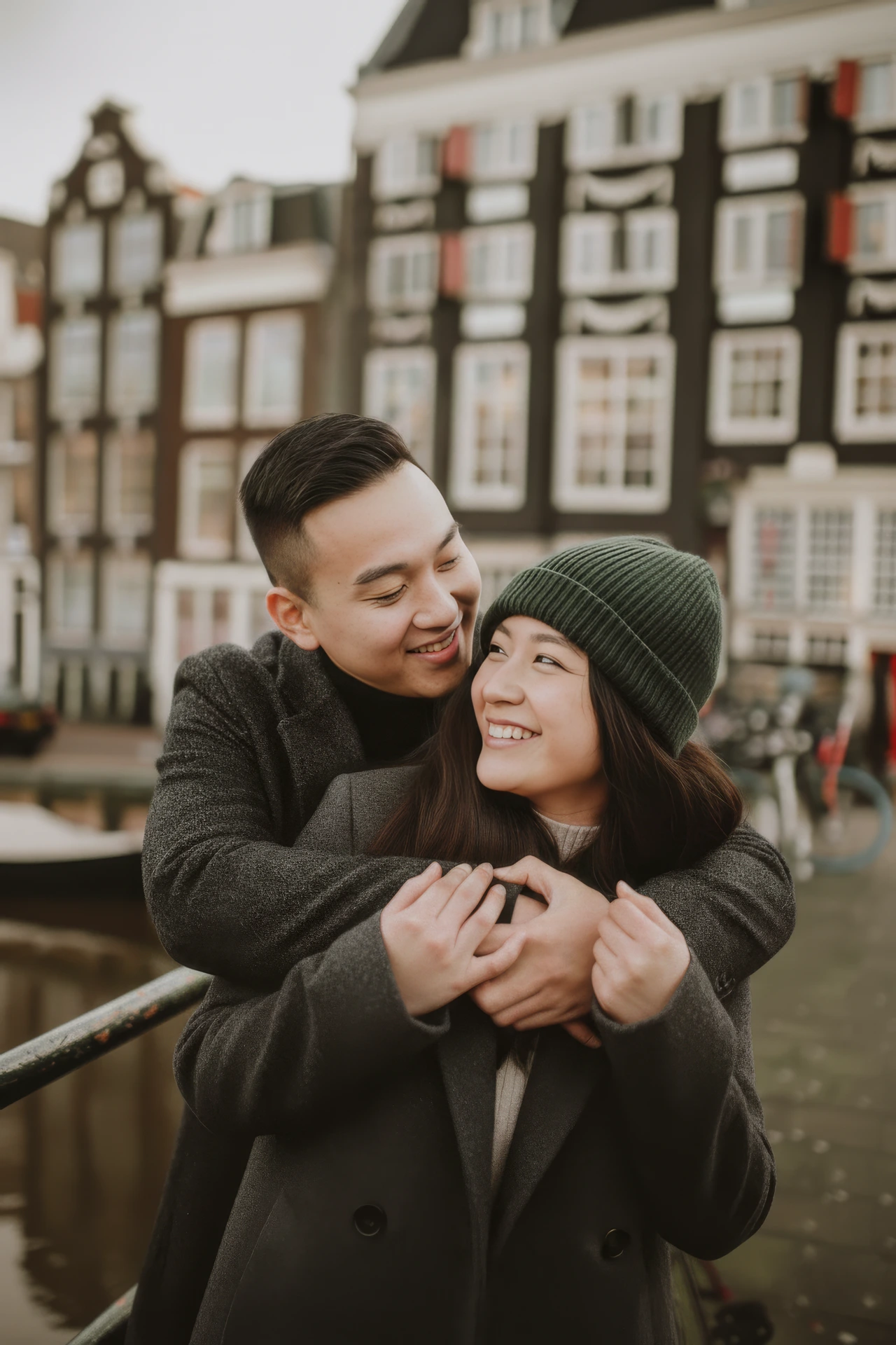 A couple hugging eachother and smiling at eachother during an engagement photoshoot in Amsterdam