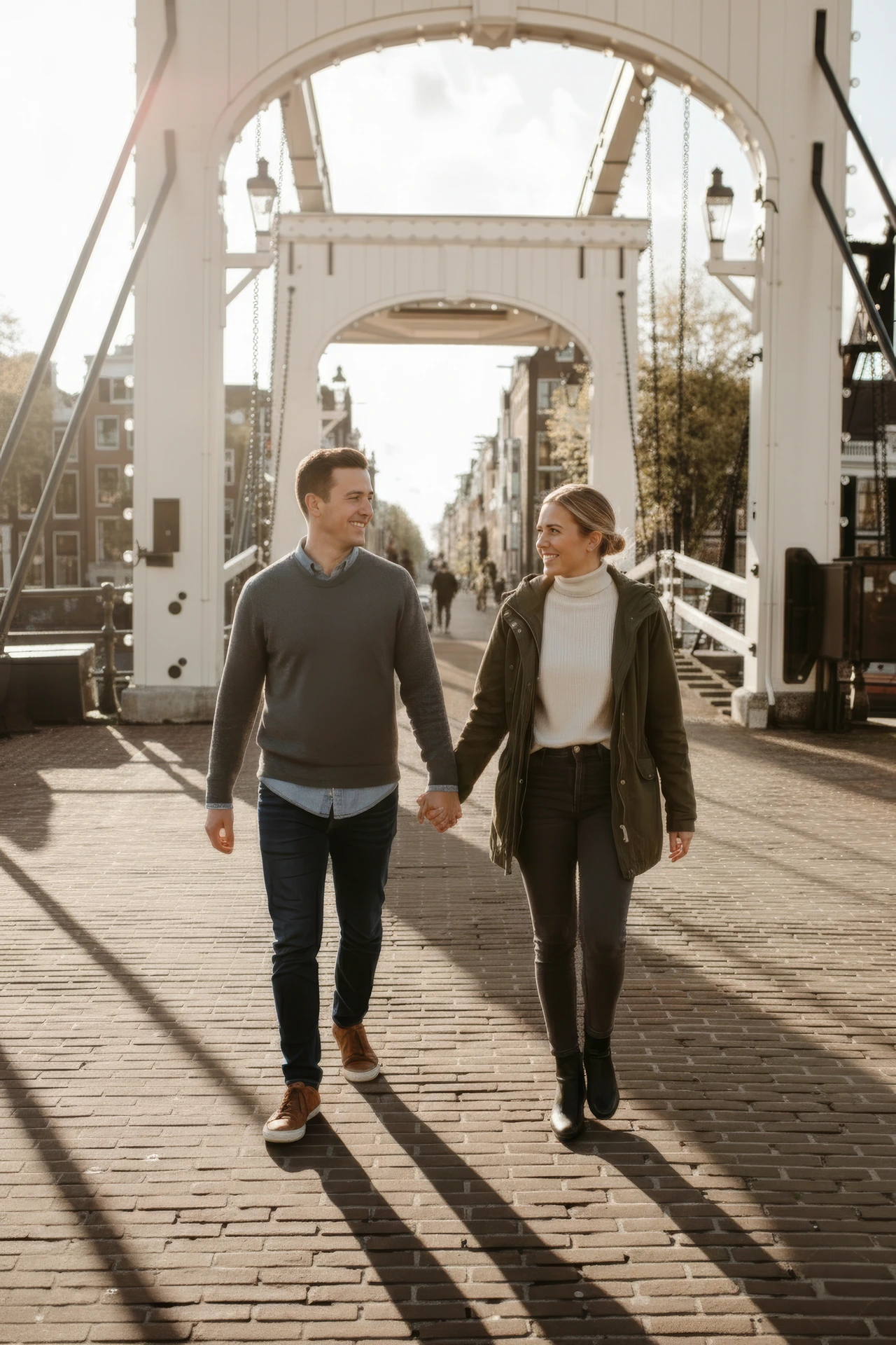 Een koppel dat wandelt bij de Magere Brug terwijl een fotograaf in Amsterdam hen vastlegt