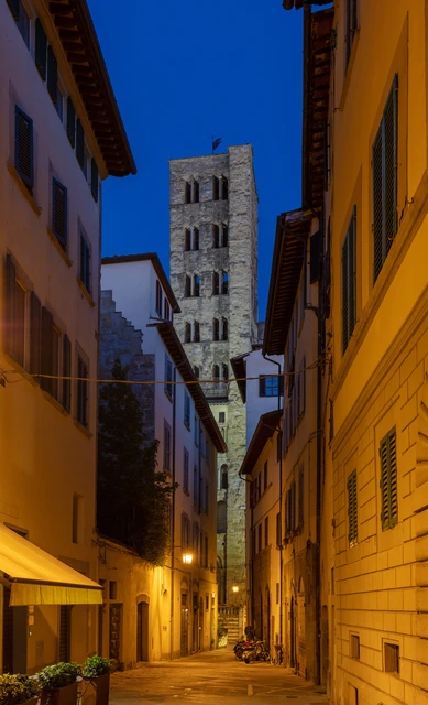 The tower of Santa Maria della Pieve above an illuminated street in Arezzo at dusk — Diego Delso / Wikimedia Commons, CC BY-SA 4.0