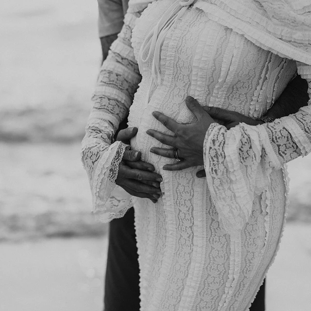 Babybauchshooting Dubai Close-up der Hände des Paares auf dem schwangeren Bauch während eines Babybauchshootings am Strand von Dubai.