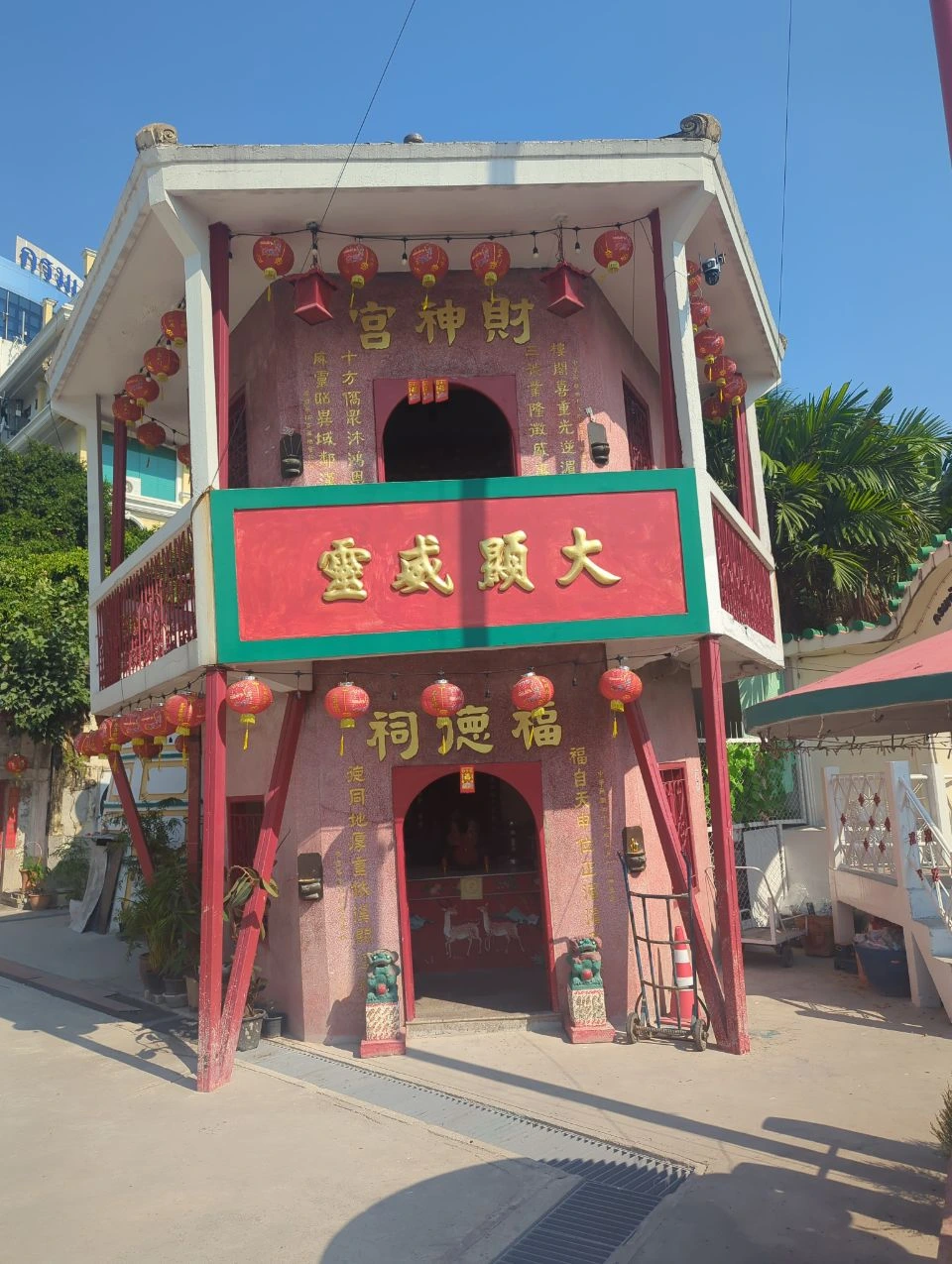 Talat Noi Photoshoot Guide - Colourful Chinese Shrine A compact red-and-green Chinese shrine with gold characters and rows of lanterns stands in bright Talat Noi daylight.