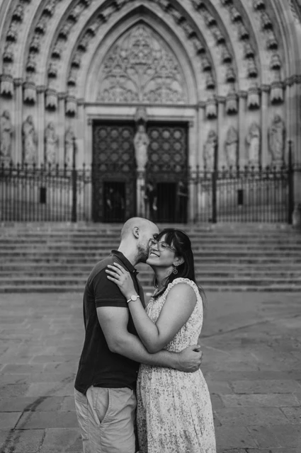 A kiss in front of Barcelona Cathedral in black and white | Barcelona anniversary photoshoot Black-and-white photograph: the couple kissing in front of the steps and carved Gothic entrance of Barcelona Cathedral during their anniversary photoshoot in Barcelona.