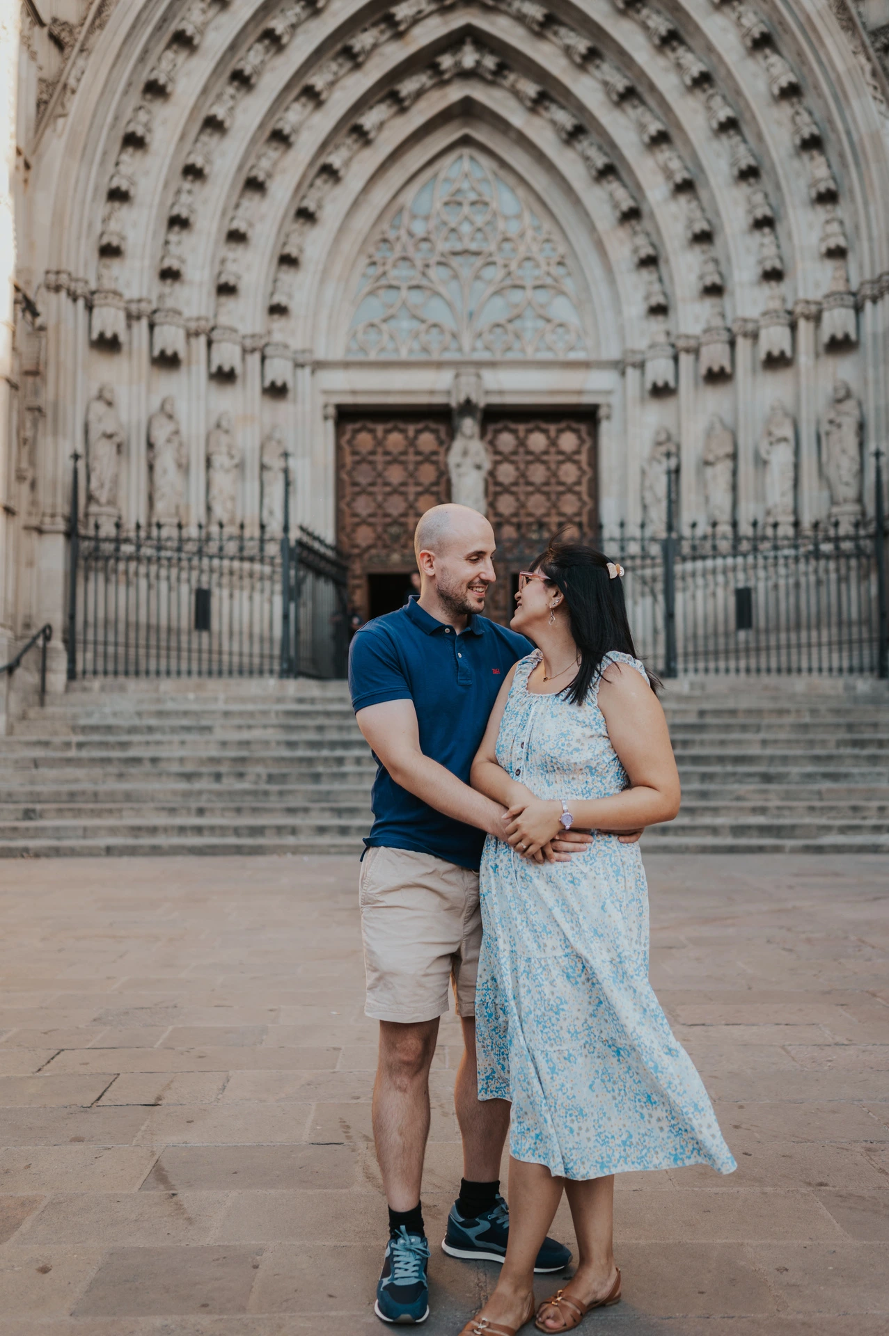 The couple standing close together in front of Barcelona Cathedral’s ornate Gothic entrance during their anniversary photoshoot in Barcelona.