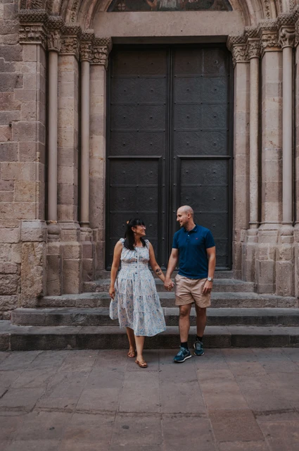 Hand in hand on the old town’s doorway steps | Barcelona anniversary photoshoot The couple holding hands on the steps in front of a carved arched doorway in the Gothic Quarter during their anniversary photoshoot in Barcelona.