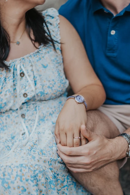 A small hand-in-hand detail from their anniversary session | Barcelona anniversary photoshoot A close-up of the couple’s hands resting together, with her pale blue floral dress and his blue polo shirt visible during their anniversary photoshoot in Barcelona.