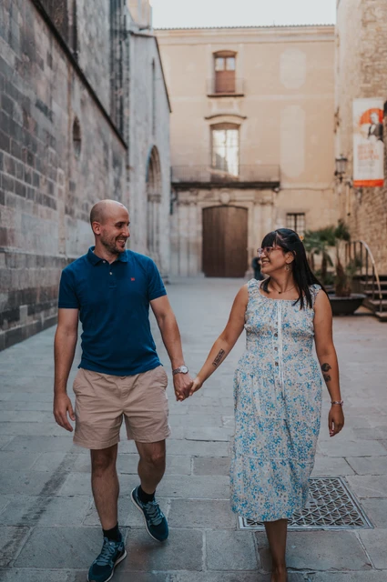 The couple walking hand in hand along a narrow stone lane in the Gothic Quarter during their anniversary photoshoot in Barcelona.