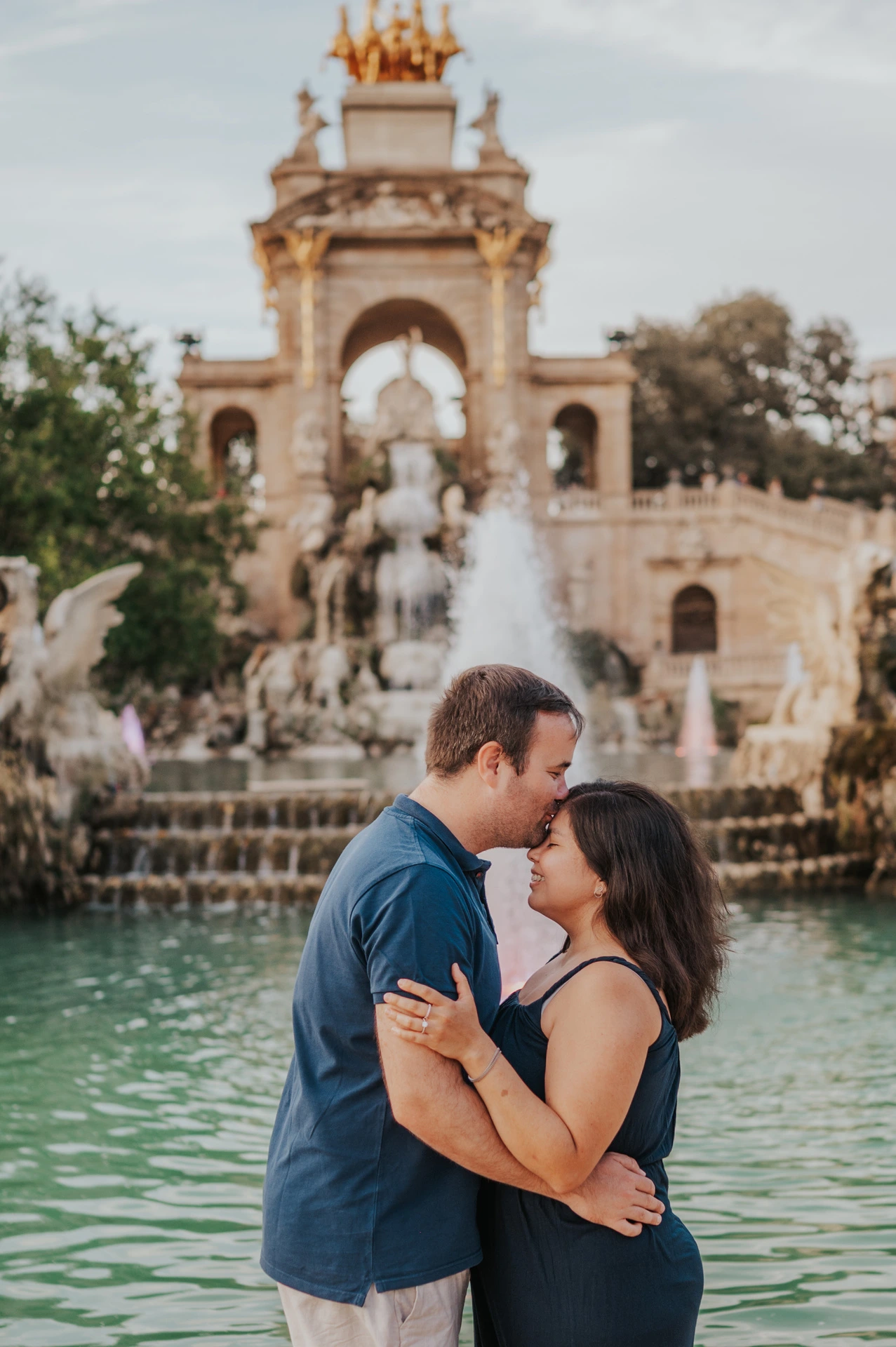 The parents standing close together in front of the fountain during their family photoshoot in Barcelona.