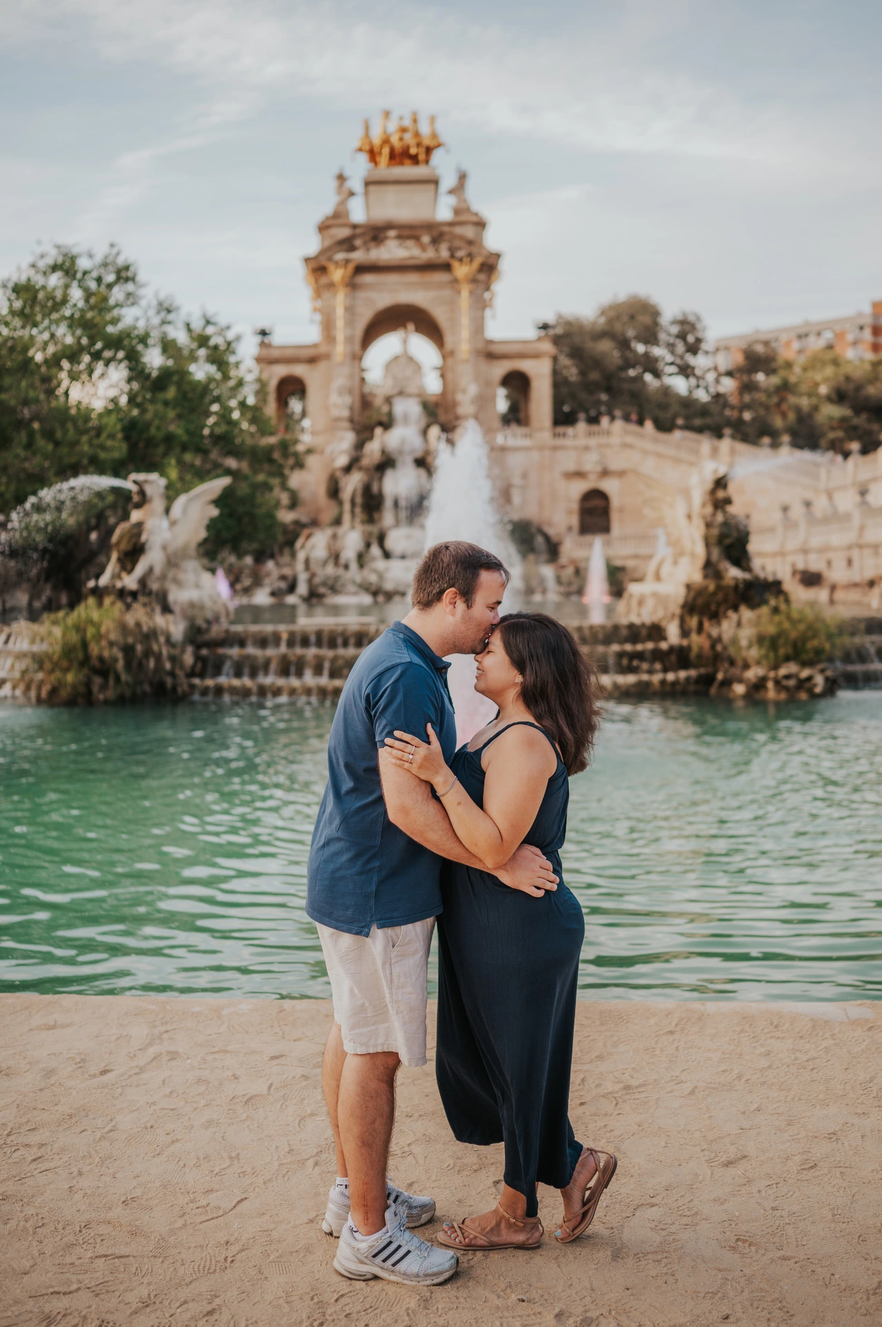 The parents standing close together in front of the fountain during their family photoshoot in Barcelona.