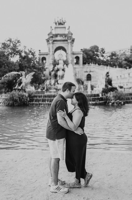 Close portraits beside the fountain pool in black and white | Barcelona family photoshoot Black-and-white photograph: the parents standing close together in front of the fountain during their family photoshoot in Barcelona.