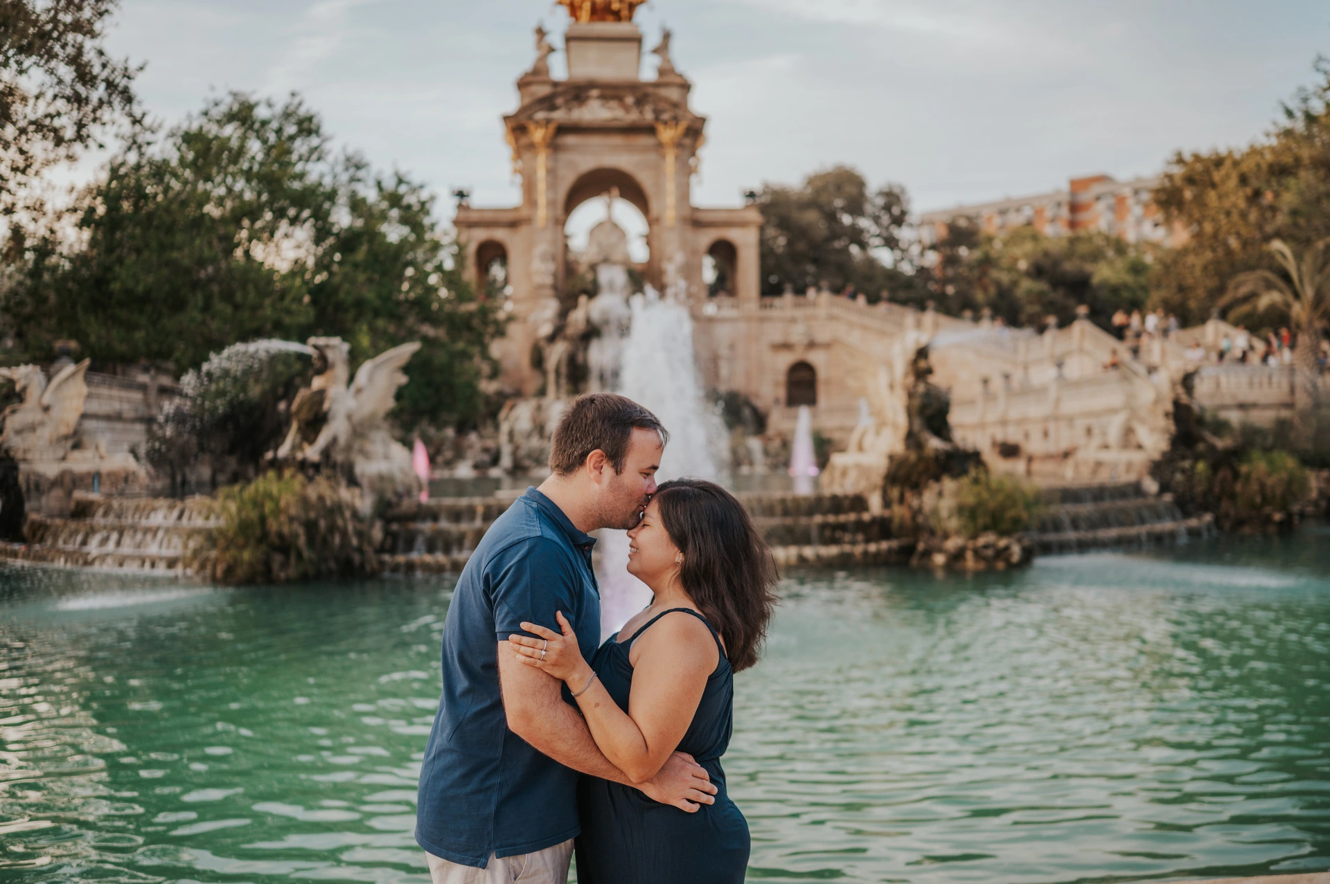 The parents standing close together in front of the fountain during their family photoshoot in Barcelona.