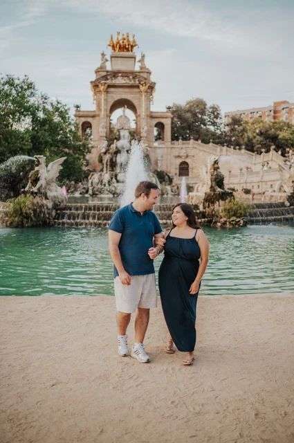 A wide couple portrait beside the fountain | Barcelona family photoshoot The parents standing together beside the fountain pool during their family photoshoot in Barcelona.