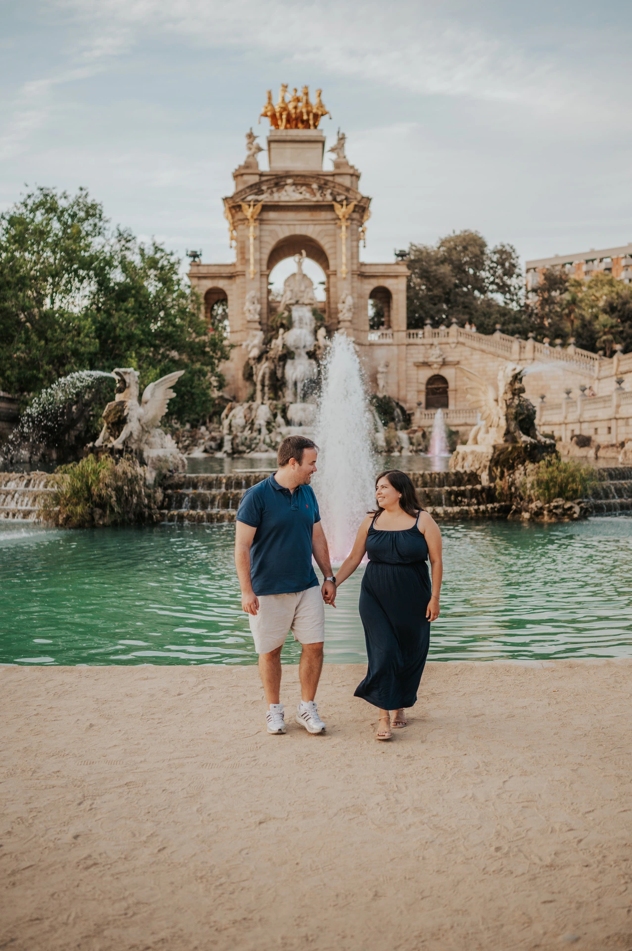 The parents standing together beside the fountain pool during their family photoshoot in Barcelona.
