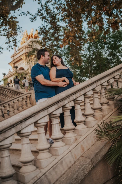 An embrace beside the staircase | Barcelona family photoshoot The parents embracing beside the sloping stone balustrade with the fountain behind them during their family photoshoot in Barcelona.