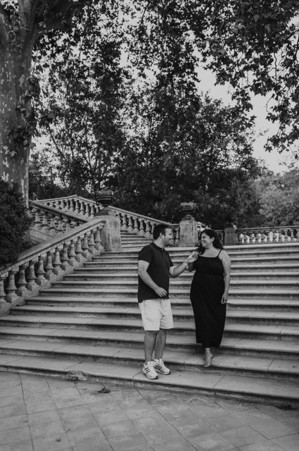 A portrait beside the park staircase in black and white | Barcelona family photoshoot Black-and-white photograph: the parents standing together in front of the broad stone staircase during their family photoshoot in Barcelona.