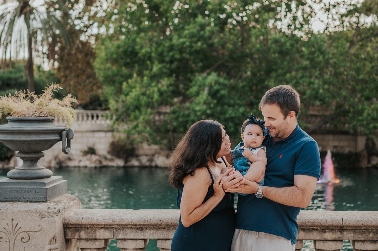 A close moment with their child | Barcelona family photoshoot The parents leaning towards their child beside the stone balustrade during their family photoshoot in Barcelona.