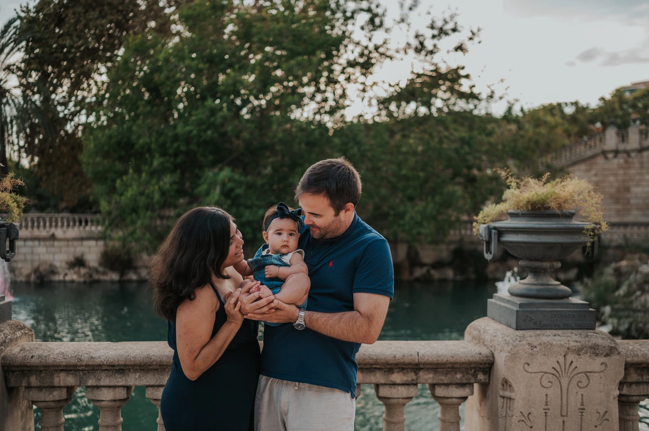 A close moment with their child | Barcelona family photoshoot The parents leaning towards their child beside the stone balustrade during their family photoshoot in Barcelona.