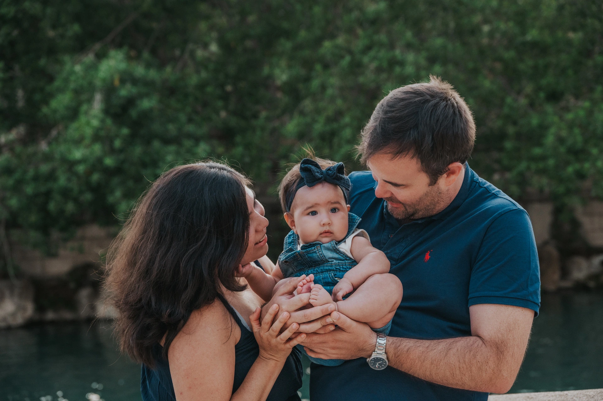 The parents leaning towards their child beside the stone balustrade during their family photoshoot in Barcelona.