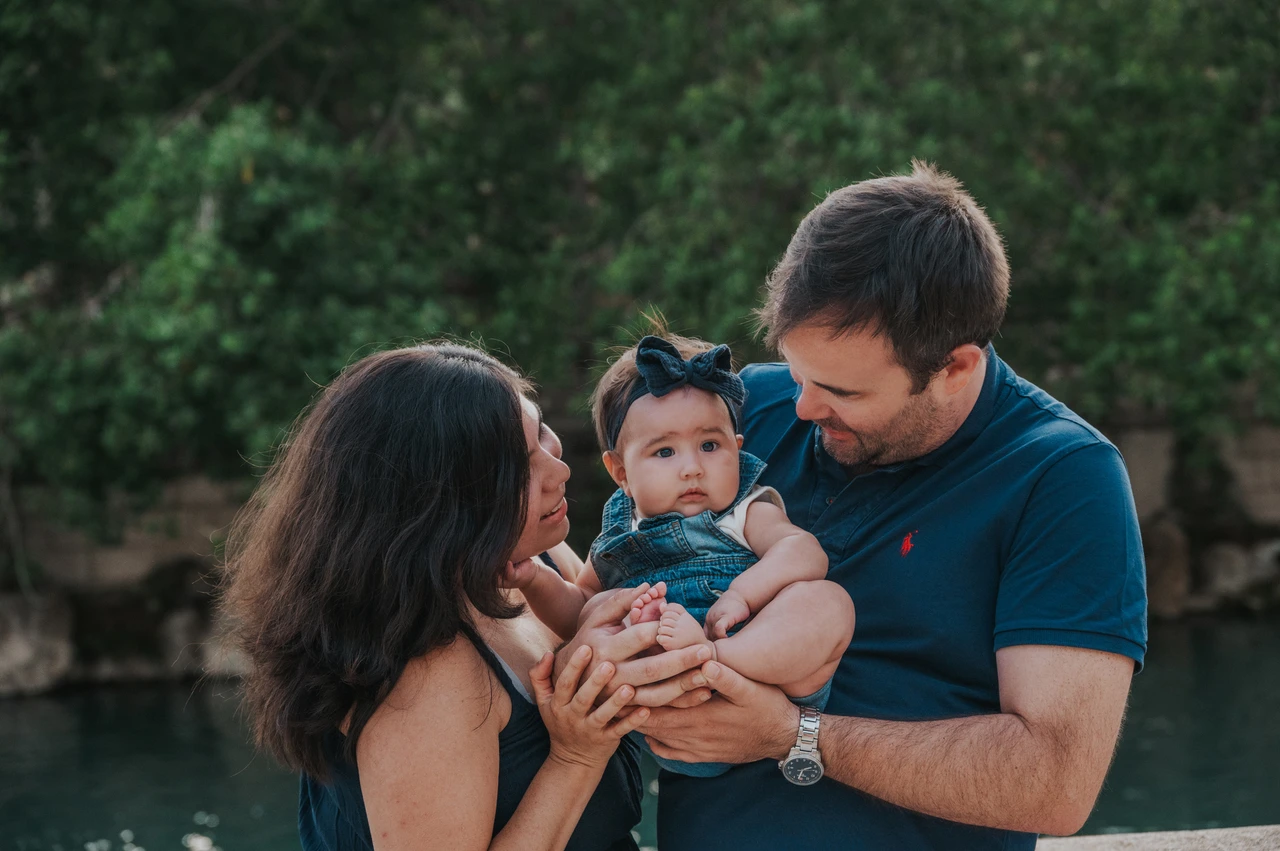 A close moment with their child | Barcelona family photoshoot The parents leaning towards their child beside the stone balustrade during their family photoshoot in Barcelona.