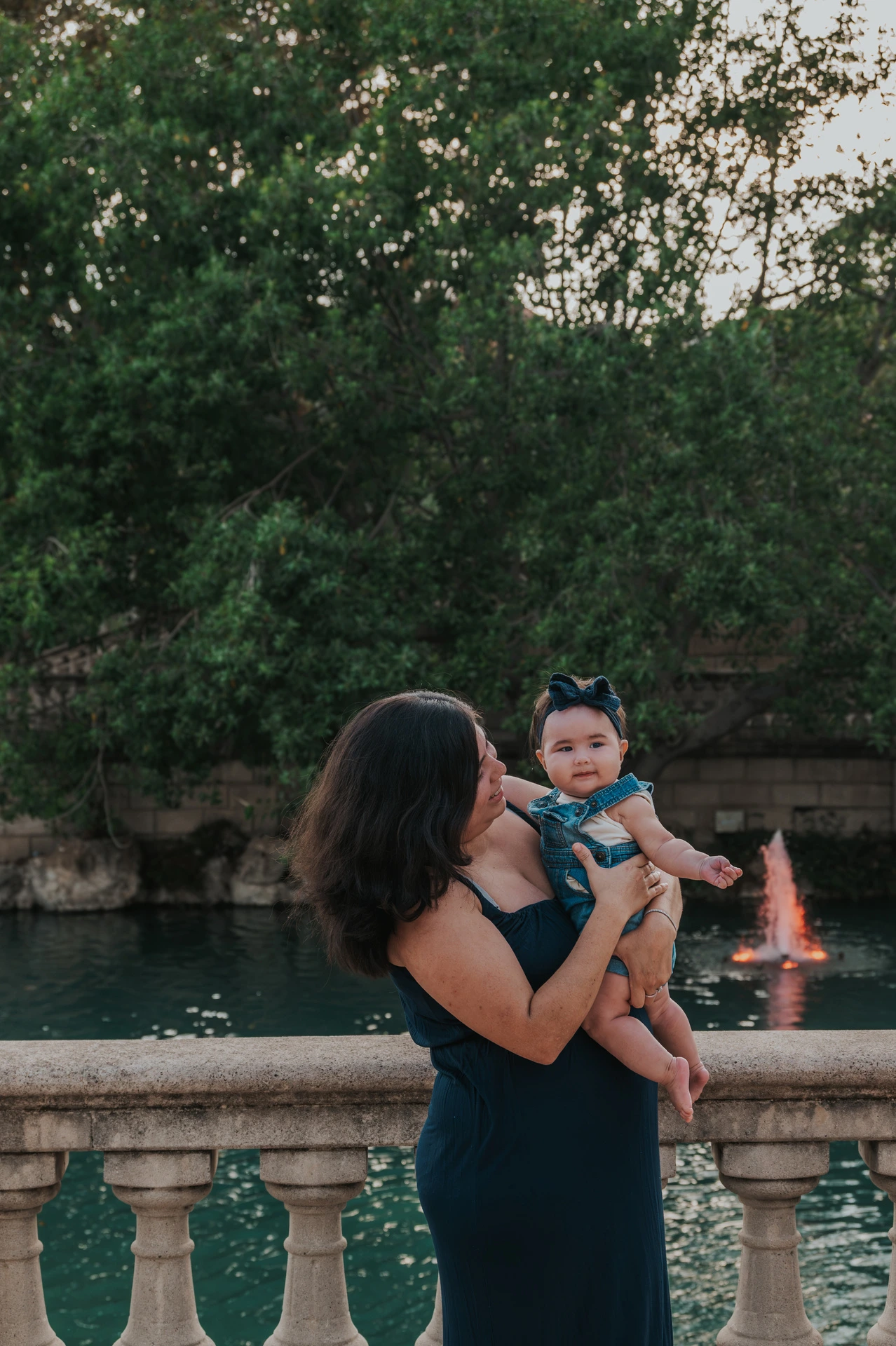 The mother holding her child beside the stone balustrade during their family photoshoot in Barcelona.