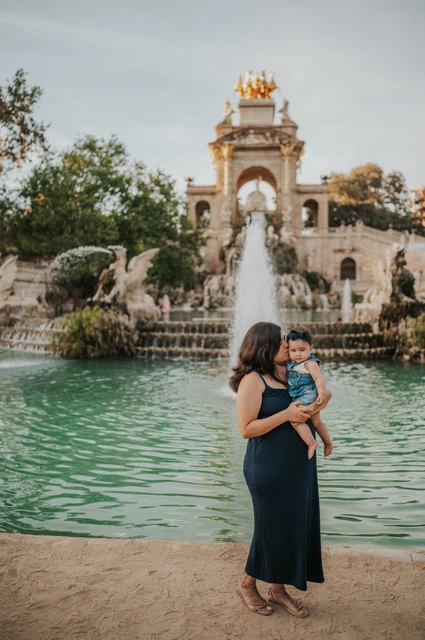 Mother and child beside the fountain | Barcelona family photoshoot The mother holding her child in front of the green fountain pool during their family photoshoot in Barcelona.