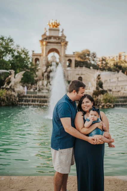 A close family moment by the water | Barcelona family photoshoot The mother holding their child while the father leans in close beside the fountain during their family photoshoot in Barcelona.