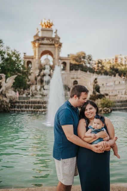 A close family moment by the water | Barcelona family photoshoot The mother holding their child while the father leans in close beside the fountain during their family photoshoot in Barcelona.