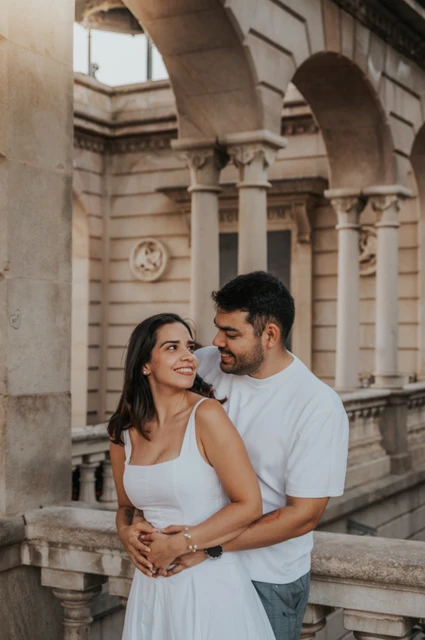 A close embrace beneath the stone arches | Barcelona engagement photoshoot The couple embracing beneath a stone arch beside the carved railing during their engagement photoshoot in Barcelona.