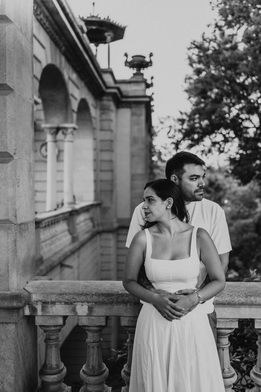 An embrace beside the archway pillar in black and white | Barcelona engagement photoshoot Black-and-white photograph: the couple embracing beside a stone pillar and looking out in different directions during their engagement photoshoot in Barcelona.