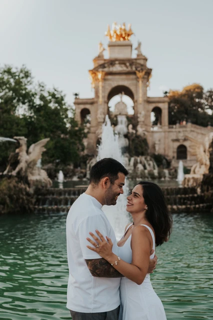 A portrait facing each other by the fountain | Barcelona engagement photoshoot The couple facing each other in front of the fountain and its golden-topped arches during their engagement photoshoot in Barcelona.