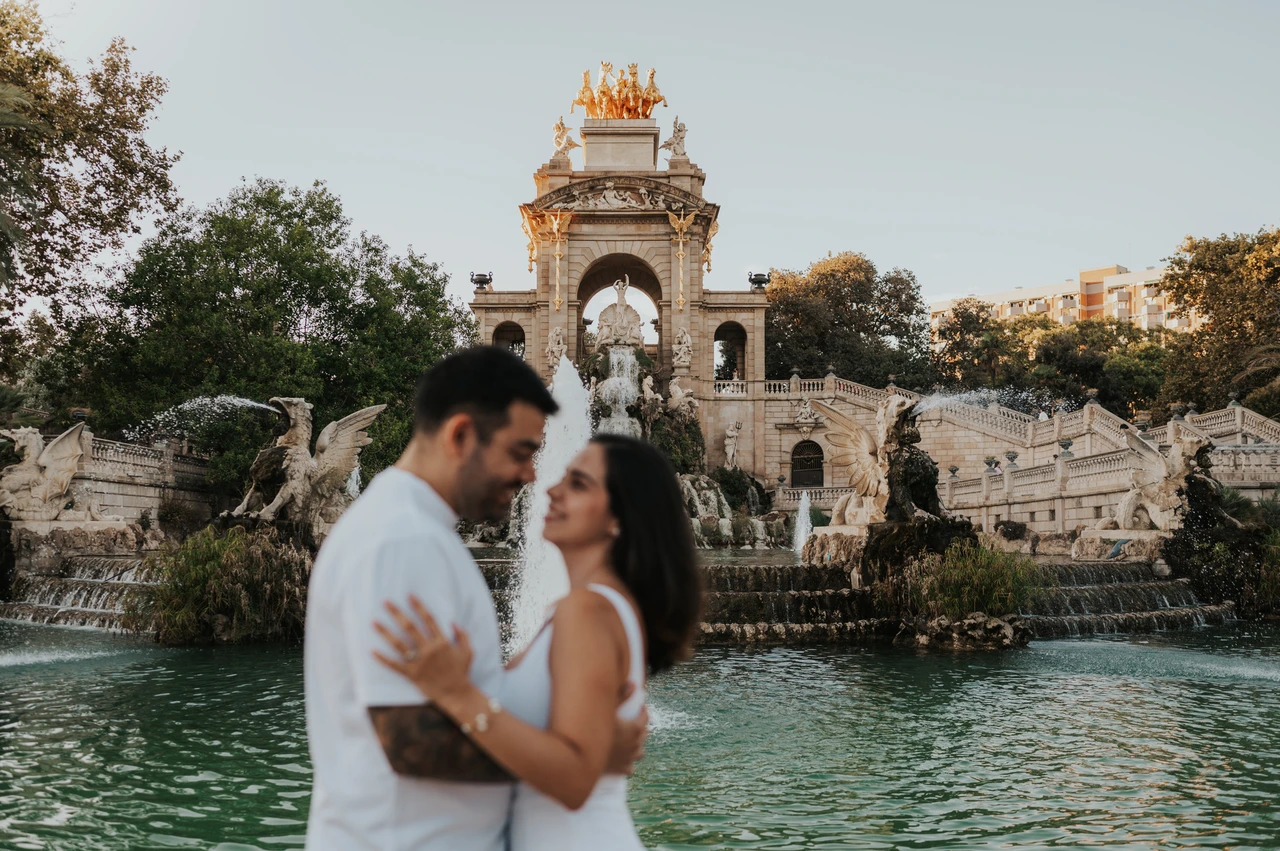 A portrait facing each other by the fountain | Barcelona engagement photoshoot The couple facing each other in front of the fountain and its golden-topped arches during their engagement photoshoot in Barcelona.