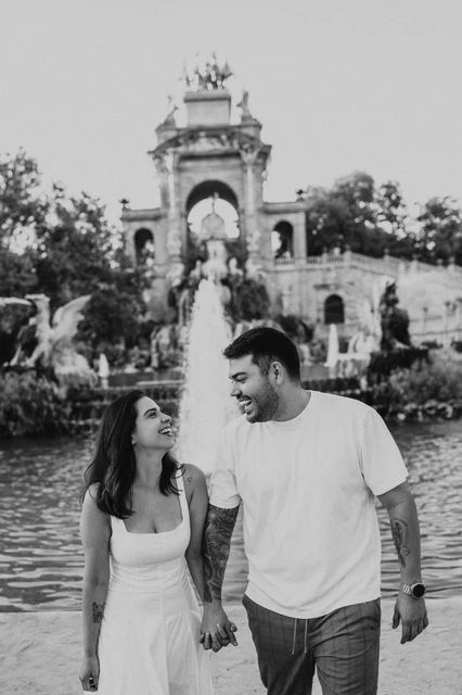 Smiles beside the fountain in black and white | Barcelona engagement photoshoot Black-and-white photograph: a close view of the couple smiling at each other as they walk by the fountain during their engagement photoshoot in Barcelona.