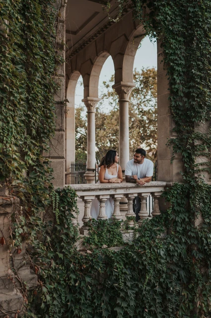 Portraits framed by ivy-covered arches | Barcelona engagement photoshoot The couple leaning towards each other behind a stone balustrade framed by ivy-covered arches during their engagement photoshoot in Barcelona.