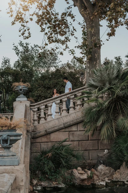 A final walk down the garden staircase | Barcelona engagement photoshoot A distant view of the couple walking down a stone staircase surrounded by greenery during their engagement photoshoot in Barcelona.