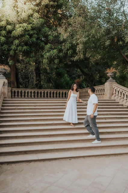 Together on the park staircase | Barcelona engagement photoshoot The couple standing together on the broad stone staircase beneath the trees during their engagement photoshoot in Barcelona.