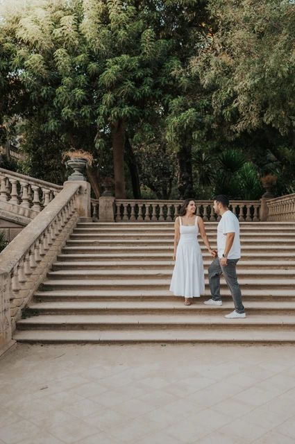 Together on the park staircase | Barcelona engagement photoshoot The couple standing together on the broad stone staircase beneath the trees during their engagement photoshoot in Barcelona.