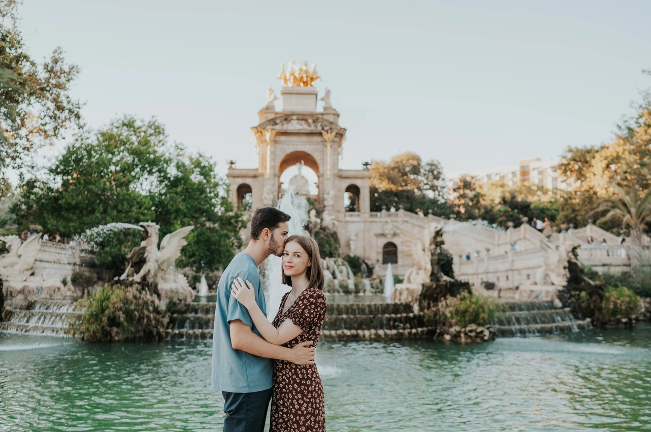 Portraits in front of the park fountain | Barcelona couple photoshoot The couple holding each other in front of the fountain pool and ornate stone monument during their couple photoshoot in Barcelona.
