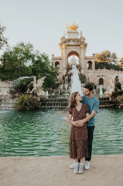 An embrace in front of the fountain | Barcelona couple photoshoot The man standing behind his partner and holding her close in front of the park fountain during their couple photoshoot in Barcelona.